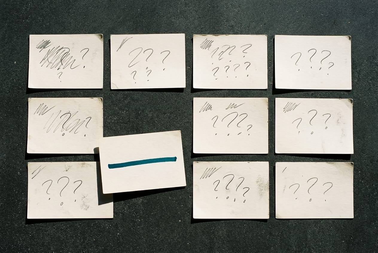 Feuilles de notes annotées à la main posées sur un plan de travail, chaque page portant une question différente